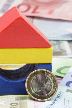 Colorful toy brick house with Euro banknotes