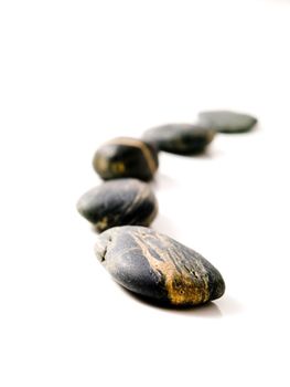 Curvy row  of pebbles with selective focus isolated on white