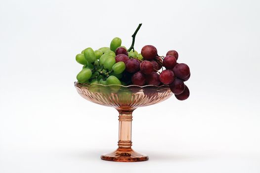 Red and green grapes in brown colored glass vase 