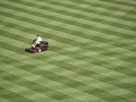 A workman mows a baseball field.