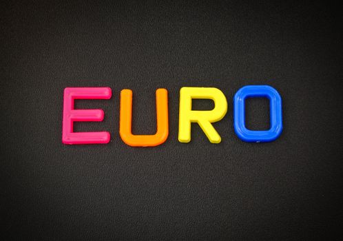 Euro in colorful toy letters on black background