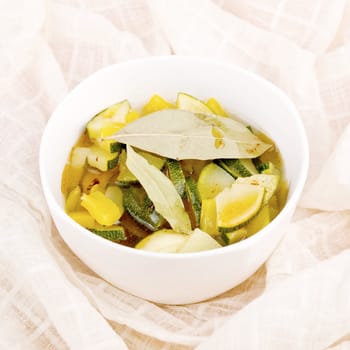 Delicious vegetarian soup made from zucchini and yellow paprika served in white porcelain bowl