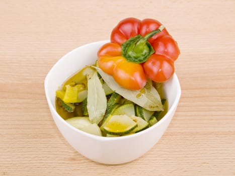Delicious vegetarian soup made from zucchini and yellow paprika served in white porcelain bowl on wooden background