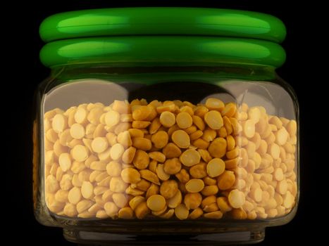 Glass container of chana dal isolated on black
