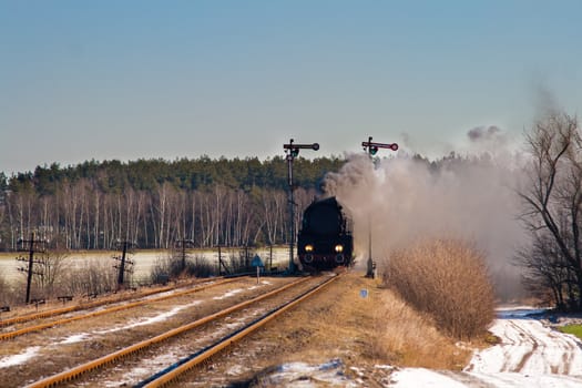 Vintage steam train passing through snowy countryside
