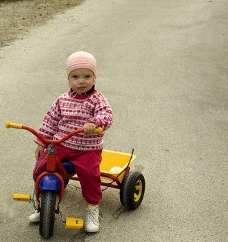 Child with funny expression sitting on a tricycle