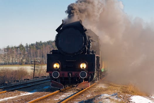 Vintage steam train passing through snowy countryside
