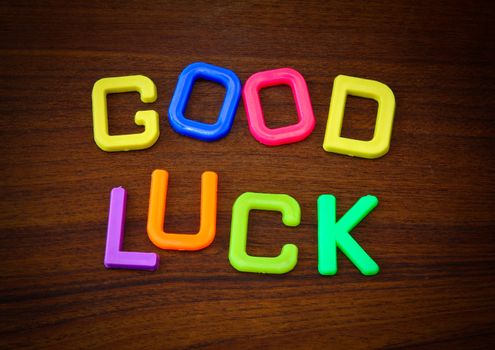 Good luck in colorful toy letters on wood background