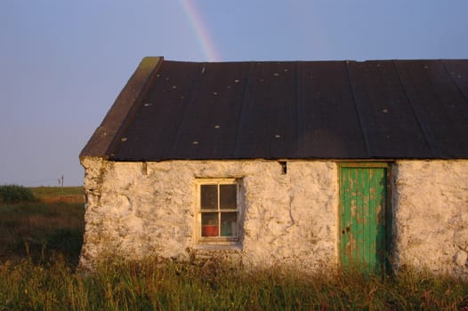 Old Shetland farmhouse with bright green door at the end of the rainbow. 