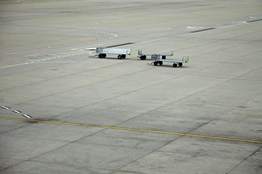 airport scene, three luggage trolleys, grey concrete