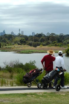 two golf player walking by a lake in Sydney, one man is pointing to Sydney tower