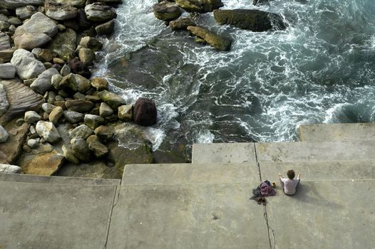 solitary man meditating, coastline, water and rocks