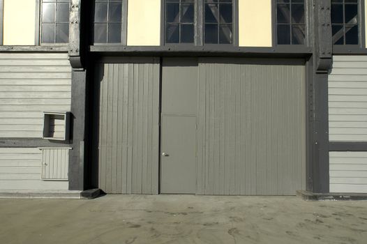 grey door to wooden warehouse, glass windows, footsteps visible on the ground