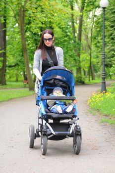 Young woman with a stroller walking in the park