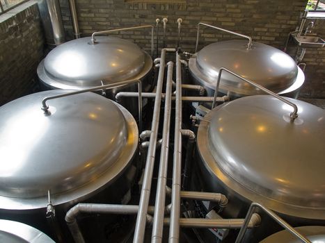 Traditional style brewery brew house inside a restaurant with metal tanks 