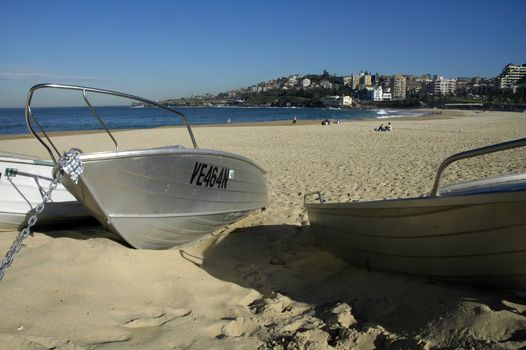 Coogee beach in Sydney; three boats in foreground anchored in sand; too cold to swim