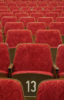 empty red wooden cinema/theater seats, number 13 in the middle,