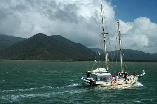 white sailboat travelling to Cairns, green sea, cloudy sky