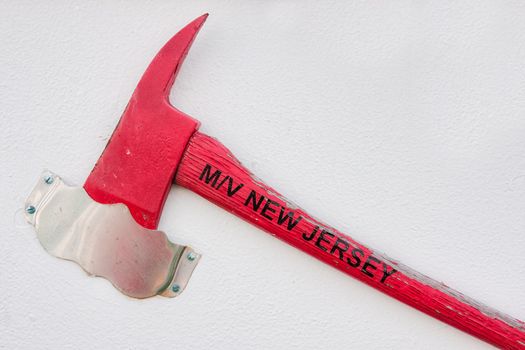 A red axe hanging on a white wall