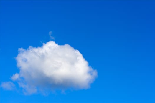 A fluffy white cumulus cloud against a blue sky