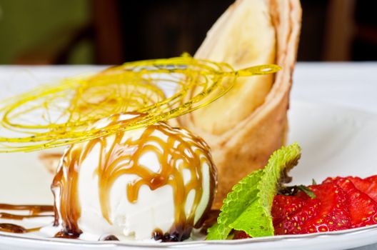 Dessert of pancake with banana, ice-cream, caramel, strawberry and mint