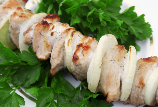 Appetizing juicy shish kebab from fresh pork in green leaves of parsley