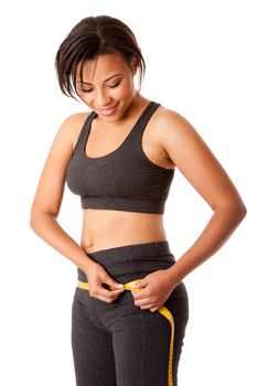 Beautiful happy toned woman weight conscious measuring her size shape around waist hips dressed sporty in grey, isolated.
