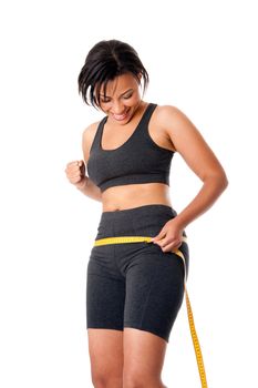 Beautiful happy toned woman weight conscious measuring her size shape around waist hips, celebrating her successful weightloss, dressed sporty in grey, isolated.