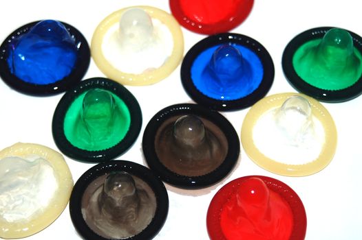 Assortment of brightly coloured condoms on white background