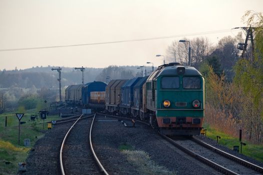 Freight train hauled by the diesel locomotive starting from the station
