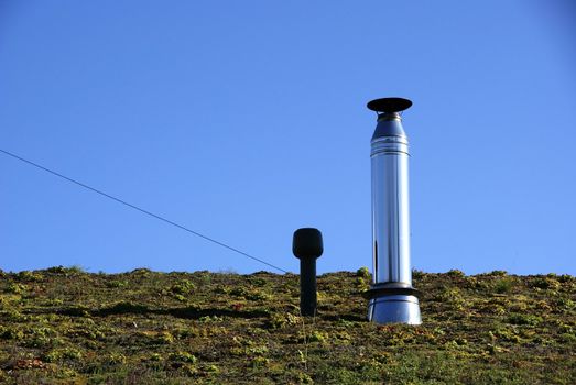 Pipes of the ventilation system on the roof with plants