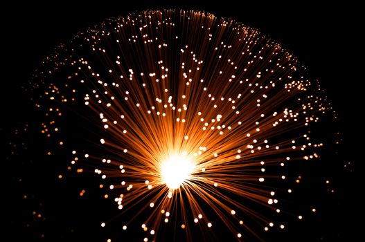 Overhead view capturing a golden illuminated fibre optic lamp against black.