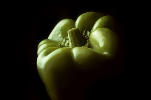 Single green Bell pepper against a black background