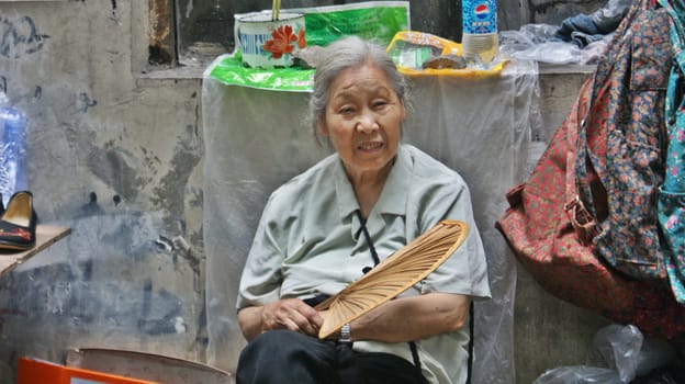 CHINA, AN OLD LADY SITTING ON THE STREET IN THE POOR AREA OF CHONGQUIN