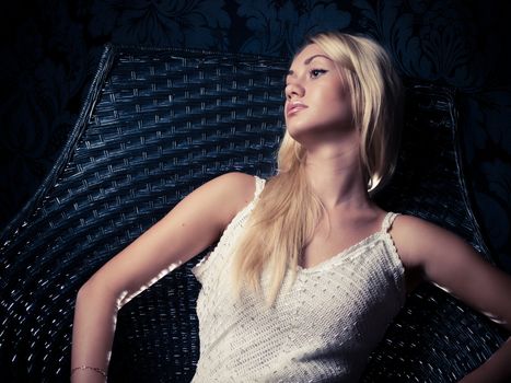 Studio portrait of a blonde model relaxing in a chair