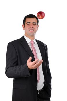 Portrait of a young cheerful businessman in a dark suit tossing an apple isolated on white