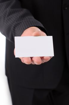 Businessman in a dark suit smiling and handing a business card isolated on white