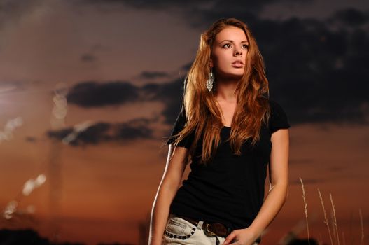 Portrait of a young attractive woman in a black shirt and jeans skirt at dusk