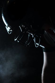 Backlit portrait of american football player in helmet ready to play