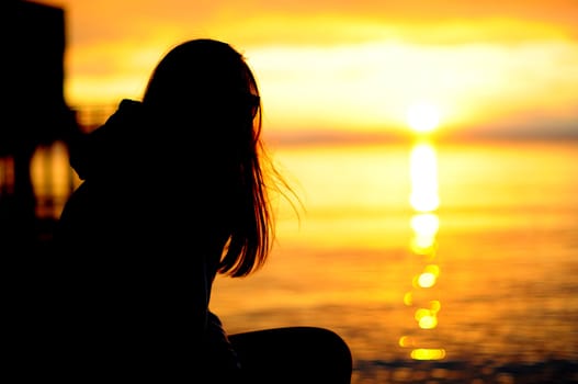 Silhouette of a young surfer girl relaxing at the seaside
