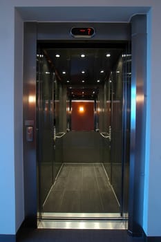 open stainless elevator with mirror, mirror reflects orange wall, level 7