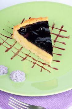 Slice of homemade blueberry marmalade and vanilla custard cream tart over a light green plate.