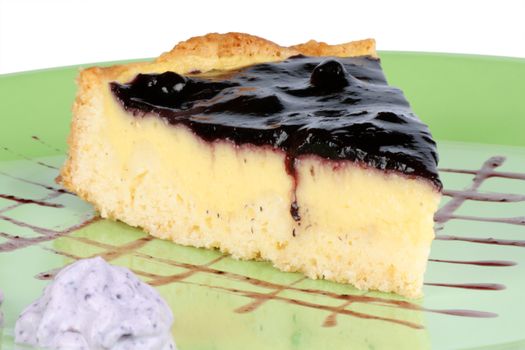 Slice of homemade blueberry marmalade and custard cream tart over a light green plate.