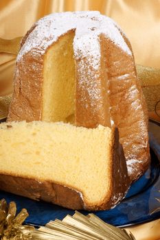 Christmas composition with Pandoro the golden cake of Verona served on a blue plate over a yellow background.