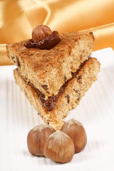 Hazelnut and chocolate cake served on a white dish over a yellow background.