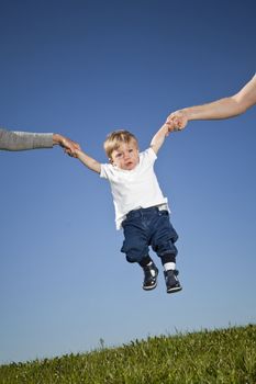 Child hanging in the air between parents hands