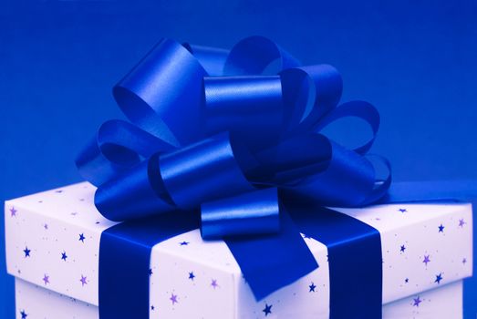 Christmas gift box with blue ribbon isolated on blue background