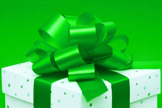 White gift box with green ribbon isolated on green background