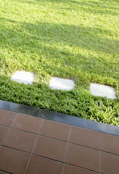 tiled patio and lush green lawn with stone flag stepping stones, vertical portrait crop area and copy space