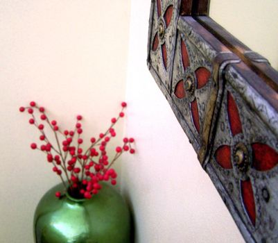 Holiday Christmas vase for interior design next to a red and silver metallic mirror. Home decoration for the holidays.